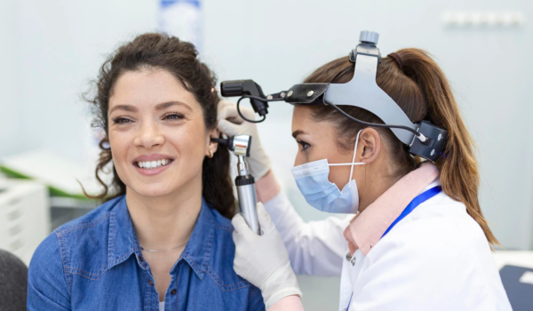 Otolaryngologist doctor checking a woman's ear with an otoscope