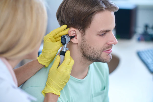 Otolaryngologist doctor checking a man's ear with an otoscope
