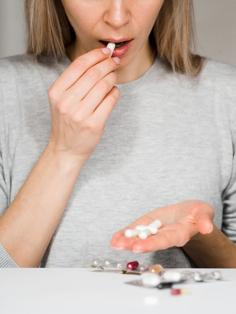 Close-up woman taking pills