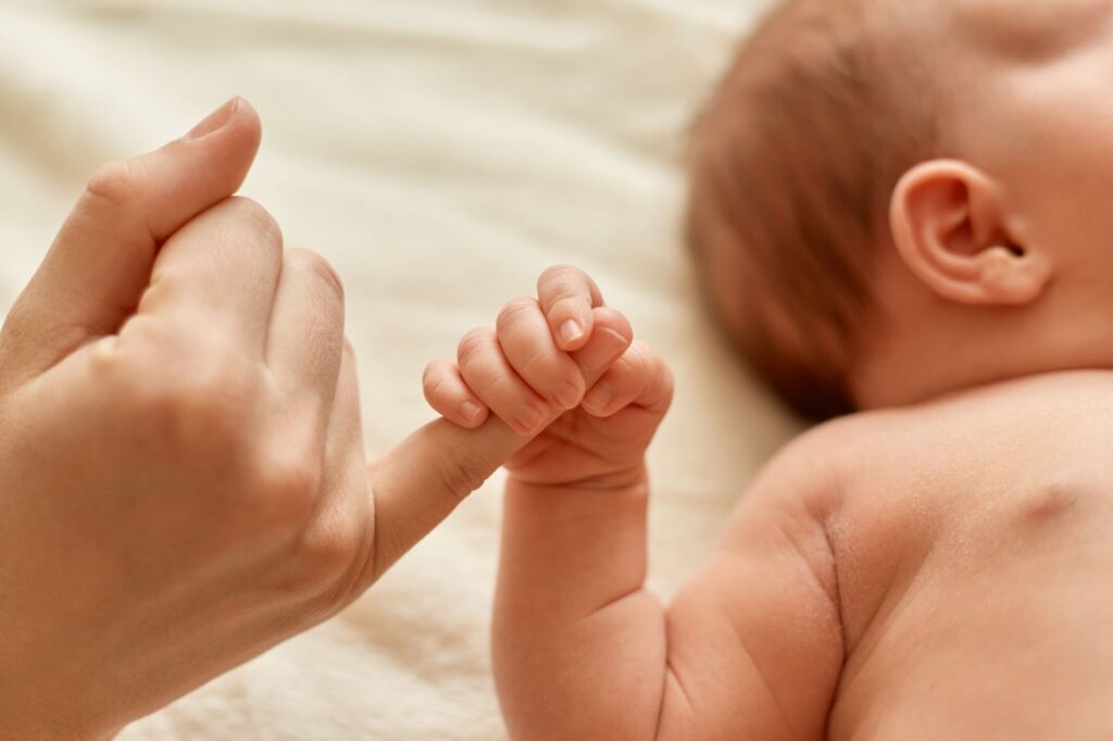 Woman holding the hand of a newborn baby