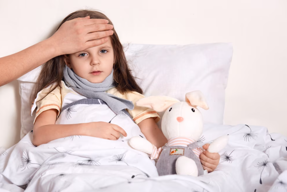 girl with a scarf on her neck in a bed with a bunny toy, mother hold hand at her forehead