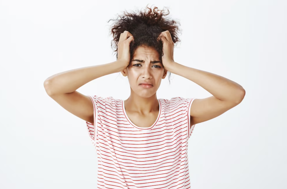 woman in a stripped t-shirt holding her head with two hands and watching straight