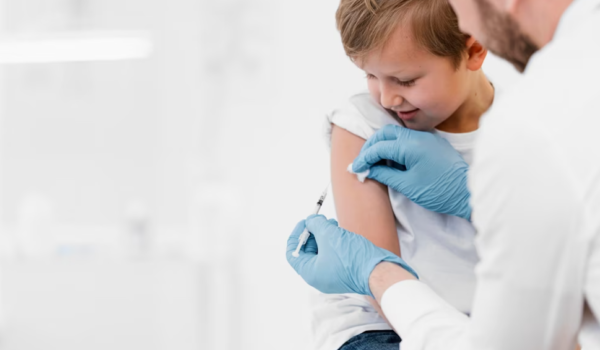 a doctor with blue gloves vaccinating a child who’s watching on the syringe