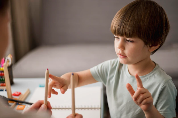 Side view of child learning to count at home with pencils