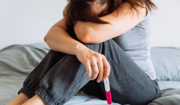 Sad woman on bed with negative pregnancy test