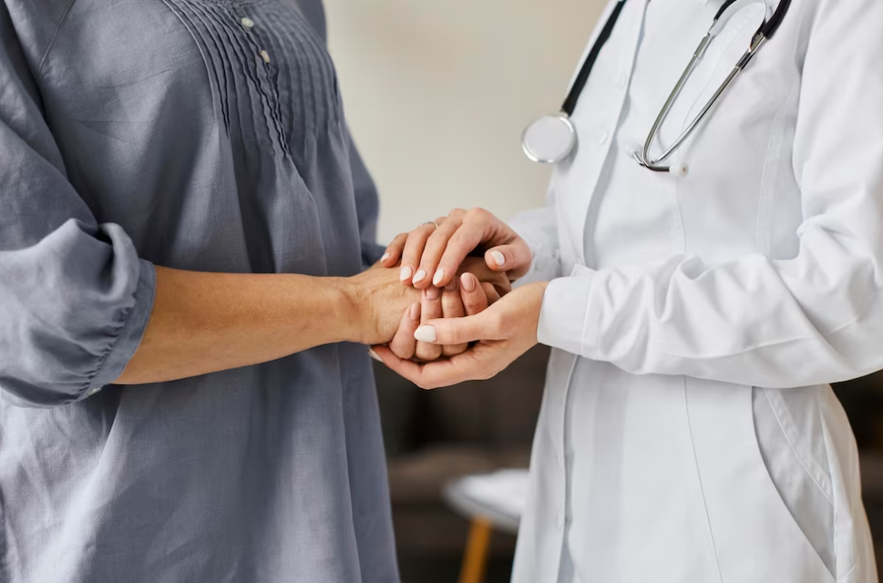 woman in dress and doctor in white medical suit and stethoscope hold each other hands